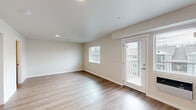Located at 4719 W Garden Springs Rd in Spokane, WA, this single-floor unit offers a clean, modern layout designed to maximize every square foot. The living room is bright and welcoming, finished with light-toned laminate hardwood flooring that runs throughout the space. Multiple windows fitted with blinds allow natural light to fill the room, while a glass-panel exterior door provides direct outdoor access and additional brightness. Neutral beige walls and white trim create a fresh, cohesive aesthetic throughout.

The combined dining and kitchen area is a functional highlight of the unit. The kitchen features rich, warm-toned cabinetry with sleek hardware, light granite-style countertops, a stainless steel sink, and black appliances including a range, over-the-range microwave, and refrigerator. A pendant light fixture accents the dining area, adding character to the open layout.

A dedicated laundry area with a full-size washer and dryer adds significant everyday convenience. The bathroom completes the layout with clean, understated finishes consistent with the rest of the unit. Throughout the space, recessed lighting and wall-unit climate control round out the practical, well-appointed design of this Spokane residence.