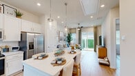 This thoughtfully designed single-floor residence offers a cohesive open-concept layout that maximizes every square foot. Light wood-look flooring flows seamlessly throughout, lending warmth and continuity to the entire space.

The kitchen serves as a central hub, showcasing white shaker cabinetry, stainless steel appliances including a French door refrigerator and electric range, and a quartz-topped island with seating for multiple guests. Pendant lighting and recessed fixtures illuminate the space, while a window over the sink invites natural light.

The kitchen opens directly into the living room, where a ceiling fan, large sliding glass door, and windows fill the room with abundant natural light and provide views of lush outdoor greenery. The living area offers a comfortable and versatile space ideal for relaxing or entertaining.

The bedroom is a serene retreat, featuring ceiling fan, multiple windows with blinds and drapes, and ample room for a full suite of furniture. The dedicated closet provides practical storage, while the adjacent full bathroom impresses with a wide quartz vanity, undermount sink, large mirror, and a glass-enclosed walk-in shower with tile surround.

A dedicated laundry room accommodates a full-size front-loading washer and dryer, with built-in shelving for added storage. A hallway connects all spaces efficiently, completing this well-planned and move-in-ready home.