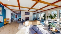 Located at 730 1/2 N First St in Minneapolis's vibrant North Loop neighborhood, this generously sized single-floor space offers an impressive open-plan layout that seamlessly blends living and dining areas. The interior is immediately defined by its signature coffered ceiling with rich warm-toned wood beams, creating a striking architectural focal point that spans the length of the space. Wide-plank light hardwood flooring runs throughout, lending a clean, contemporary aesthetic underfoot.

The living area centers around a sleek, tile-surround fireplace with a natural wood mantle, providing a welcoming anchor for multiple seating arrangements. Floor-to-ceiling windows line the perimeter walls, flooding the interior with natural light while offering open views of the surrounding greenery and outdoor patio areas. Sliding glass doors connect directly to an exterior courtyard, extending the sense of space and enabling seamless indoor-outdoor flow.

The dining zone accommodates generous group seating, complemented by a kitchen island ideal for casual gatherings. A dedicated lounge nook features bistro-height tables positioned directly in front of large picture windows, perfect for individual work or informal meetings. Bold accent walls in deep teal add visual depth and modern character, while carefully curated artwork enhances the contemporary ambiance throughout this thoughtfully designed communal space.