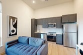 Located at 9420 Grand Blvd in Upper Marlboro, MD, this single-floor, three-bedroom, one-bathroom residence offers a well-designed layout with modern finishes throughout. The open-concept living, dining, and kitchen area serves as the heart of the home, featuring soaring ceilings that enhance the sense of space. Large windows flood the living area with natural light and offer views of the surrounding greenery. The kitchen is outfitted with gray shaker-style cabinetry, quartz countertops, a white subway tile backsplash, and a full suite of stainless steel appliances including a refrigerator, range, microwave, and dishwasher. Light wood-tone flooring flows consistently throughout the home. A central hallway connects the three bedrooms, an office, and the full bathroom. The primary bedroom benefits from generous natural light through large windows with outdoor views. The bathroom features a subway-tiled tub-shower combo, a quartz-topped vanity with a gray cabinet, and wood-tone flooring. Four closets, including walk-in style storage with wire shelving, provide ample organization. A dedicated laundry area adds everyday convenience to this thoughtfully planned residence.