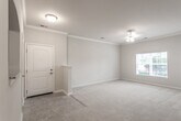 Located at 7190 Harbour Towne Pkwy S in Suffolk, Virginia, this single-floor residence offers a well-designed layout with a neutral color palette and consistent finishes throughout. The galley-style kitchen is a standout feature, showcasing rich dark cabinetry, granite countertops, a stainless steel sink, tile flooring, and black appliances including a range and built-in microwave. An arched pass-through connects the kitchen to the adjacent dining area, which is accented by a pendant light fixture and transitions seamlessly into plush carpeted living spaces. The spacious living room is adorned with crown molding, a ceiling fan, and a door providing access to the outdoors, allowing for natural light to fill the space. The bedrooms are generously sized with soft carpeting, ceiling fans, and ample closet space, including a walk-in closet with built-in shelving in one room. The bathrooms are well-appointed with dark vanity cabinetry, granite countertops, tiled flooring, and a full tub-shower combination. A dedicated laundry area is also present within the unit. The overall ambiance is clean, cohesive, and functional, making this a comfortable and practical living space.