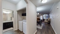 This single-floor residence is thoughtfully designed with a cohesive aesthetic that balances functionality and style. The entryway opens into a hallway finished with wood-look flooring and crown molding, leading to a dining area illuminated by a contemporary chandelier. The dining space connects seamlessly to the living room, which features a ceiling fan, large windows with floor-length drapes, and a glass-paneled door that fills the room with natural light.

The kitchen is a standout, outfitted with dark shaker-style cabinetry, granite countertops, a subway tile backsplash, and stainless steel appliances, including a range, microwave, and refrigerator. A dedicated laundry closet houses a full-size, side-by-side washer and dryer with overhead shelving for added storage.

The primary bedroom offers plush carpeting, a ceiling fan, generous closet space, and large windows. Its en-suite bathroom features a granite-topped vanity with dark cabinetry and a framed mirror. A second bedroom also includes carpeting, natural light, and closet access. Crown molding and neutral tones are consistent throughout, lending the residence a polished, unified appearance.