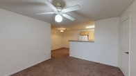 This single-floor residence offers a practical and comfortable layout designed for everyday living. The entry opens into a spacious living area with neutral-toned carpet, a textured ceiling, and a ceiling fan with a light fixture, creating a welcoming atmosphere. A peninsula-style kitchen is positioned adjacent to the living space, featuring warm wood cabinetry, dark countertops, a double-basin stainless steel sink, tile flooring, and white appliances including a range, refrigerator, dishwasher, and built-in microwave. A central hallway connects the main living area to the private rooms, lined with doors leading to closets and additional spaces. The bedrooms are generously sized, each finished with plush carpeting, ceiling fans, and windows fitted with blinds that allow for natural light and privacy. The primary bedroom includes access to a walk-in closet, adding notable storage convenience. The full bathroom is cleanly appointed with tile flooring, a single-sink vanity with wood cabinetry, a lighted mirror, and a shower-tub combination. Throughout the residence, a consistent palette of white walls and warm beige carpeting creates a cohesive, neutral aesthetic that is move-in ready and easy to personalize.