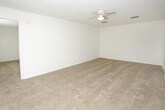 This single-floor, 3-bedroom, 2-bathroom residence offers a thoughtfully organized layout designed for comfortable everyday living. The living area is bright and welcoming, featuring warm neutral carpet, a ceiling fan with light fixture, and large vertical-blind-covered sliding glass doors that allow abundant natural light to fill the room. The kitchen is well-equipped with white raised-panel cabinetry, light granite-style countertops, a tile backsplash, and wood-look flooring. Black appliances — including an electric range, dishwasher, and refrigerator — provide a clean contrast to the bright cabinetry, and a window above the sink brings in additional natural light. Each of the three bedrooms is carpeted and features a ceiling fan, creating a comfortable and restful atmosphere. The bedrooms offer ample floor space and are served by windows fitted with blinds for privacy and light control. The two bathrooms are finished with wood-look flooring and include tub-shower combinations with clean white surrounds, providing functional and easy-to-maintain spaces. Throughout the unit, textured ceilings, neutral white walls, and consistent flooring choices create a cohesive and move-in-ready environment suited for a variety of lifestyles.