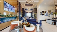 This single-floor clubhouse is a masterclass in contemporary luxury design, combining elegance with functionality across a series of thoughtfully curated spaces. The grand lobby immediately commands attention with its coffered ceilings adorned with statement chandeliers, a striking navy velvet curved sofa, and an eclectic mix of designer seating in rich terracotta, cream, and deep blue tones. Large-format white tile and warm wood-inlay flooring create a bold visual corridor through the heart of the space.

A dedicated co-working area features sleek marble-topped counters and deep blue upholstered seating beneath pendant lighting, ideal for productivity. The leasing or welcome area showcases textured mosaic tile walls, arched backlit mirrors with gold accents, and a curved reception counter — all contributing to a boutique hotel-like atmosphere.

Adjacent to the main lounge, a billiards and game lounge area offers floor-to-ceiling windows that flood the space with natural light and outdoor views. A neon "Game Over" sign anchors a retro arcade corner complete with the world's largest Pac-Man machine, complemented by stylish wingback chairs. Throughout, the design palette of navy, gold, and warm neutrals delivers a cohesive, upscale ambiance.