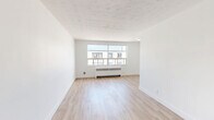This well-appointed one-bedroom, one-bathroom unit is located at 318–352 Patricia Ave in Kitchener, Ontario, offering a thoughtfully designed layout across a single floor. The interior features light hardwood flooring throughout the living spaces, paired with crisp white walls that create a clean and airy atmosphere.

The living room is generously proportioned, benefiting from large windows that invite abundant natural light and offer views of the surrounding neighbourhood. Radiant baseboard heaters are positioned beneath the windows, providing efficient warmth throughout the colder months.

The kitchen is well-equipped with white cabinetry, grey stone-effect countertops, a stainless steel sink, and a classic white subway tile backsplash. Stainless steel appliances, including an electric range, microwave, and dishwasher, complete this functional cooking space.

The bedroom is a comfortable size, featuring a built-in closet with panel doors and direct access to the hallway. It also includes a large window that fills the room with natural light.

The bathroom continues the subway tile aesthetic seen in the kitchen, with floor-to-ceiling white tiles surrounding a full soaking tub and shower combination, accented by chrome fixtures for a polished finish.

A connecting hallway ties all areas together, contributing to the unit's efficient and practical flow.