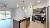 This single-floor residence offers a thoughtfully designed open-concept layout that seamlessly connects the kitchen and living areas. Light hardwood-style flooring runs throughout the main living spaces, creating a bright and cohesive aesthetic.

The kitchen serves as the centerpiece of the home, anchored by a central island with a granite countertop, an undermount sink, pendant lighting overhead, and a built-in dishwasher. Dark wood cabinetry with sleek hardware provides ample storage and a contemporary contrast against the light surroundings. A full suite of stainless steel appliances — including a refrigerator, electric range, and over-the-range microwave — completes the space. A subway tile backsplash adds a clean, polished detail to the cooking area.

Arched doorways add an architectural touch that lends character and visual interest as you move through the space. The open living area is generously proportioned, benefiting from recessed lighting and a neutral color palette that enhances the sense of openness.

The bathrooms are finished with the same dark wood cabinetry and granite countertops found in the kitchen, maintaining design consistency throughout. Each bathroom features light hardwood-style flooring, a soaking tub with a shower combination, and clean white tile surround — offering a functional and well-appointed space.