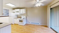 Located in Lakewood, Washington, this two-bedroom, one-bathroom unit offers a well-organized single-floor layout designed for comfortable everyday living. The galley-style kitchen is bright and efficient, featuring white cabinetry, a double-basin sink, laminate wood flooring, a skylight, and a window that brings in natural light. White appliances including a refrigerator, electric range, microwave, and dishwasher are included. The adjoining living area is anchored by a classic brick fireplace, adding warmth and character to the space, and is finished with a ceiling fan overhead. Both bedrooms are carpeted and feature baseboard heating, with the primary bedroom offering a large window and the second bedroom benefiting from natural light and direct hallway access. The primary bedroom includes a full-width sliding door closet with warm wood-toned panels. The bathroom is clean and functional, with a tub-shower combination, a white vanity, and light wood-style flooring. A dedicated laundry area houses a full-size GE washer and dryer set alongside built-in shelving and a water heater. Hallways connect the rooms efficiently throughout the unit, making the overall layout feel practical and easy to navigate.