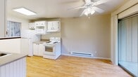 Located in Lakewood, Washington, this two-bedroom, one-bathroom unit offers a well-organized single-floor layout designed for comfortable everyday living. The galley-style kitchen is bright and efficient, featuring white cabinetry, a double-basin sink, laminate wood flooring, a skylight, and a window that brings in natural light. White appliances including a refrigerator, electric range, microwave, and dishwasher are included. The adjoining living area is anchored by a classic brick fireplace, adding warmth and character to the space, and is finished with a ceiling fan overhead. Both bedrooms are carpeted and feature baseboard heating, with the primary bedroom offering a large window and the second bedroom benefiting from natural light and direct hallway access. The primary bedroom includes a full-width sliding door closet with warm wood-toned panels. The bathroom is clean and functional, with a tub-shower combination, a white vanity, and light wood-style flooring. A dedicated laundry area houses a full-size GE washer and dryer set alongside built-in shelving and a water heater. Hallways connect the rooms efficiently throughout the unit, making the overall layout feel practical and easy to navigate.