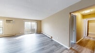 Located at 2701 Brunswick Ave N in Crystal, MN, this 2-bedroom, 1-bathroom unit offers a practical and well-appointed single-floor layout. The open living room is a bright, welcoming space featuring light gray luxury vinyl plank flooring, neutral warm-toned walls, a textured ceiling, and a sliding glass door that opens to a private balcony with outdoor views. A wall-mounted air conditioning unit and baseboard heating provide year-round comfort.

The kitchen is a standout feature, offering rich dark wood cabinetry, granite countertops, a tile backsplash, and stainless steel appliances including a range, microwave, and refrigerator. Track lighting and LVP flooring complete this functional galley-style space.

Both bedrooms are well-sized, filled with natural light from large windows that frame views of the surrounding neighborhood and greenery. Each bedroom includes a dedicated closet with bi-fold wood doors and built-in rod storage. The primary bedroom offers additional space and is connected to hallway access.

The bathroom features classic white tile surrounding a full tub/shower combo, mosaic tile flooring, and warm neutral walls. Two hallways provide connectivity throughout the unit, and the dark-toned entry door adds a clean, modern touch to the overall design.