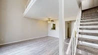 This two-story home at 400 Waterdance Ln in Arlington, Texas offers a practical and well-organized layout spread across two floors. The main level hosts an open-concept kitchen and living room area, a pantry, two bathrooms, and ample closet storage. The living room features light gray wood-look flooring, a ceiling fan with light fixture, and a textured ceiling, while a staircase with white railings and carpet-covered treads leads to the upper level. A pass-through window connects the kitchen to the living area, adding an interactive design element. The kitchen is equipped with white cabinetry, laminate countertops, a dishwasher, and a stainless steel refrigerator, all set on matching wood-look flooring.

The upper floor is home to the generously sized primary bedroom, carpeted for comfort and featuring a ceiling fan, a closet, and neutral-toned walls. An additional open loft-style space on the upper level, also carpeted and bordered by white railings, provides flexible use as a sitting or office area. Tall windows on the upper floor invite abundant natural light and offer views of the surrounding exterior.

The bathrooms are clean and functional, each featuring a vanity with a granite-style countertop, white cabinetry, and a tub/shower combination. Throughout, the home maintains a neutral color palette, creating a bright and cohesive atmosphere.