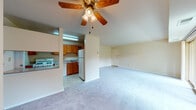This single-floor residence offers a practical and comfortable layout designed for everyday living. The open-plan living and dining area is finished with plush wall-to-wall carpeting and neutral walls, creating a bright and welcoming atmosphere. A ceiling fan with a light fixture serves as a central feature, while a large sliding glass door floods the space with natural light and provides direct access to a balcony overlooking lush greenery and surrounding landscaping.

The kitchen is positioned adjacent to the living area, partially separated by a half-wall that maintains an open feel. It features warm oak cabinetry with ample upper and lower storage, light speckled countertops, a double sink, a gas range, a dishwasher, and a full-size refrigerator. Tile flooring and under-cabinet lighting complete the functional space.

The primary bedroom is generously sized with soft carpet, neutral walls, and a large sliding glass door that opens to the balcony, offering the same pleasant outdoor views. A double bifold closet provides substantial storage. A second bedroom offers its own closet and comfortable proportions.

The full bathroom includes a single-sink vanity with warm wood cabinetry, a mirrored medicine cabinet, a toilet, and a full bathtub with shower combination, all finished in light, neutral tones.
