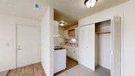Located at 2219 Normandy Dr in Michigan City, Indiana, this single-floor unit offers a practical and well-organized layout across several distinct living areas. The galley-style kitchen is efficiently designed with white cabinetry, ample upper and lower storage, light granite-style countertops, a gas range, refrigerator, and a double sink — all set atop wood-look flooring that adds warmth to the space. Adjacent to the kitchen is a closet with louvered bi-fold doors, providing convenient storage near the entry. The living area is generously proportioned, featuring plush carpet, a textured ceiling, and a large sliding glass door fitted with vertical blinds that fills the room with natural light. Multiple bedrooms are carpeted and feature large windows with exterior views of greenery and the surrounding neighborhood, as well as sizable closets with bi-fold doors and built-in shelving. The full bathroom includes a tile-surround soaking tub and shower combination, a vanity with storage, and wood-look flooring. Throughout the unit, a neutral color palette of soft whites and warm beiges creates a clean, cohesive aesthetic. HVAC vents and a thermostat are integrated throughout for year-round comfort.