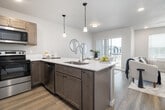 Located at 116 S Kcid Rd in Caldwell, Idaho, this well-designed two-story home offers a functional and modern layout across two floors. The main level features an open-concept living, dining, and kitchen area, where light wood-look flooring flows throughout. The kitchen is outfitted with taupe shaker-style cabinetry, white countertops, and a full suite of stainless steel appliances, including a refrigerator with ice maker, electric range, and built-in microwave. The living area is bright and welcoming, with large windows fitted with horizontal blinds that allow for natural light control. The attached two-car garage provides ample vehicle and storage space, with a concrete floor, drywalled walls, and a automatic opener. Upstairs, three carpeted bedrooms are connected by a hallway lined with clean white panel doors and black hardware accents. The primary bedroom offers generous proportions with direct hallway access. Two full bathrooms serve the upper level, one featuring a tub-shower combination with black-framed glass doors, wood-tone vanity, and wood-look tile flooring. A dedicated laundry room houses a full-size washer and dryer with overhead shelving. Two closets with hanging rods provide additional storage throughout the home.