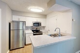 Located at 4900 Heather Dr in Dearborn, MI, this two-bedroom, one-bathroom residence offers a practical and well-appointed single-floor layout. The space is finished with durable hardwood-style flooring throughout, neutral gray and beige tones on the walls, and textured ceilings that lend a consistent aesthetic across all rooms.

The kitchen is a standout feature, showcasing white shaker cabinetry, speckled quartz countertops, a subway tile backsplash, and a full suite of stainless steel appliances including a refrigerator, electric range, and over-the-range microwave. A peninsula with an integrated sink adds both prep space and a casual dining option.

The living room benefits from multiple windows fitted with blinds, allowing for ample natural light, and includes a door leading to a private balcony. The primary bedroom is generously sized and is accompanied by a second bedroom and two closets for added storage. A ceiling fan is installed in one of the bedrooms for year-round comfort.

The bathroom is clean and functional, featuring a tiled shower-tub combination, a white vanity with quartz countertops, and wood-look flooring. An in-unit laundry area adds everyday convenience, completing this efficient and move-in-ready home.
