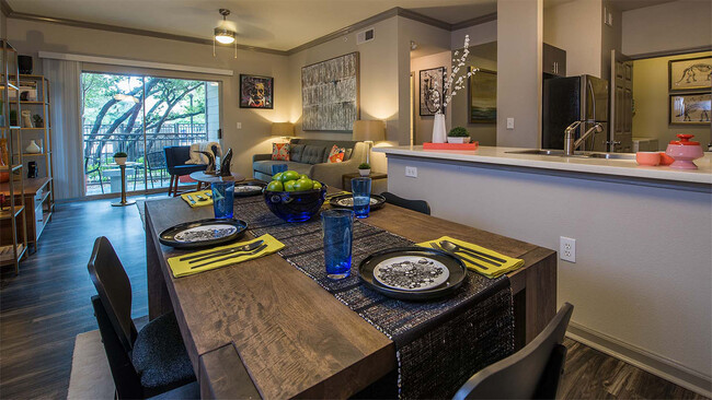 Cocina del apartamento con electrodomésticos de acero inoxidable, comedor y sala de estar con pisos de madera. - Griffis Lakeline Station