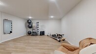 Located at 3425 Eischen Ct in Duluth, MN, this dedicated fitness studio offers a clean, modern environment designed for focused exercise and recovery. The single-room space is finished with light-toned luxury vinyl plank flooring throughout, lending a bright and polished aesthetic that complements the crisp white walls and smooth ceiling with recessed lighting.

The studio is thoughtfully equipped for a variety of workout modalities. A multi-tiered equipment rack holds an assortment of medicine balls, kettlebells, and resistance bands in multiple colors, providing a comprehensive range of strength and conditioning tools. A professional-grade Pilates reformer sits prominently in the room, offering a dedicated apparatus for low-impact, full-body training. Exercise stability balls are neatly stacked on a dedicated storage tower, maximizing floor space efficiency.

A wall-mounted mirror panel enhances the sense of space and supports form-checking during workouts. A ductless mini-split HVAC unit ensures climate control year-round, keeping the environment comfortable regardless of Minnesota's seasonal extremes. Two doors provide convenient access points, while a tan massage chair positioned in the corner serves as a recovery station. The open floor plan allows ample room for floor exercises, stretching, or additional equipment. Overall, this studio presents a functional and inviting space for personal fitness and wellness.