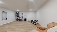 Located at 3425 Eischen Ct in Duluth, MN, this dedicated fitness studio offers a clean, modern environment designed for focused exercise and recovery. The single-room space is finished with light-toned luxury vinyl plank flooring throughout, lending a bright and polished aesthetic that complements the crisp white walls and smooth ceiling with recessed lighting.

The studio is thoughtfully equipped for a variety of workout modalities. A multi-tiered equipment rack holds an assortment of medicine balls, kettlebells, and resistance bands in multiple colors, providing a comprehensive range of strength and conditioning tools. A professional-grade Pilates reformer sits prominently in the room, offering a dedicated apparatus for low-impact, full-body training. Exercise stability balls are neatly stacked on a dedicated storage tower, maximizing floor space efficiency.

A wall-mounted mirror panel enhances the sense of space and supports form-checking during workouts. A ductless mini-split HVAC unit ensures climate control year-round, keeping the environment comfortable regardless of Minnesota's seasonal extremes. Two doors provide convenient access points, while a tan massage chair positioned in the corner serves as a recovery station. The open floor plan allows ample room for floor exercises, stretching, or additional equipment. Overall, this studio presents a functional and inviting space for personal fitness and wellness.
