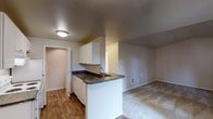 This 2-bedroom, 2-bathroom single-floor residence offers a practical and comfortable layout designed to maximize livability. The kitchen serves as a central feature, showcasing white cabinetry, dark granite-style countertops, and a peninsula with a built-in sink that doubles as a breakfast bar. The peninsula creates a natural boundary between the kitchen and the adjacent living area while maintaining an open, connected feel throughout the space.

The kitchen is equipped with a dishwasher and offers ample cabinet storage overhead, complemented by hardwood-style flooring that adds warmth and durability underfoot. The transition into the living area is seamless, where neutral carpet provides a softer surface and contributes to a cozy atmosphere. The living space is generously sized, offering flexibility for various furniture arrangements.

Neutral wall tones throughout create a clean, versatile backdrop suitable for a range of décor styles. The textured ceiling adds subtle visual interest, while flush-mount lighting ensures the space remains well-lit. A hallway visible from the kitchen leads to additional rooms, including the two bedrooms and bathrooms, reinforcing the thoughtful flow of the floor plan.