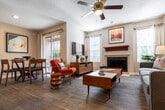 This single-story residence offers a thoughtfully designed layout that balances comfort and functionality across its living, dining, kitchen, and bedroom spaces. The open living area serves as the heart of the unit, featuring wood-look plank flooring, a ceiling fan with light fixture, and a tile-surround fireplace with a dark wood mantel as a focal point. Multiple windows flood the space with natural light, while a sliding glass door provides direct access to a private balcony with outdoor views. A dedicated dining area sits adjacent to the living room, creating a seamless flow for everyday living and entertaining.

The kitchen is equipped with stainless steel appliances, including a range, microwave, and refrigerator, complemented by rich wood cabinetry and granite countertops that extend to a breakfast bar. Textured ceilings are consistent throughout the unit.

The bedroom features plush carpeting, a ceiling fan, and multiple windows that allow ample natural light. A walk-in closet provides generous storage. A secondary bedroom mirrors similar design elements. The bathroom includes a wood-framed vanity mirror, granite-topped cabinetry, a wall-mounted light bar, and wood-look flooring, reflecting a consistent design language throughout the residence.