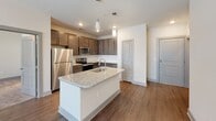 Located at 404 Gallop Ln in Charlotte, NC, this single-story residence offers a well-appointed, modern interior with a thoughtful layout and quality finishes throughout. The kitchen serves as a focal point of the home, showcasing rich dark-toned cabinetry, a subway tile backsplash, stainless steel appliances including a refrigerator, microwave, and range, and a central island topped with light granite countertops and an undermount sink with a modern faucet — all illuminated by stylish pendant lighting. Hardwood-style flooring flows through the main living areas, adding warmth and continuity. The living space is bright and open, benefiting from natural light streaming through blinds-fitted windows. The bedrooms feature plush carpeting, ceiling fans with integrated lighting, and windows that invite outdoor views. The bathrooms are well-equipped, with one featuring a dark-cabinetry vanity with granite countertops, a large framed mirror, and access to a walk-in closet, while another includes a full tub-shower combination with brushed nickel fixtures. A dedicated laundry room houses a full-size washer and dryer alongside overhead wire shelving for additional storage, adding practical convenience to daily living.