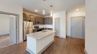 Located at 404 Gallop Ln in Charlotte, NC, this single-story residence offers a well-appointed, modern interior with a thoughtful layout and quality finishes throughout. The kitchen serves as a focal point of the home, showcasing rich dark-toned cabinetry, a subway tile backsplash, stainless steel appliances including a refrigerator, microwave, and range, and a central island topped with light granite countertops and an undermount sink with a modern faucet — all illuminated by stylish pendant lighting. Hardwood-style flooring flows through the main living areas, adding warmth and continuity. The living space is bright and open, benefiting from natural light streaming through blinds-fitted windows. The bedrooms feature plush carpeting, ceiling fans with integrated lighting, and windows that invite outdoor views. The bathrooms are well-equipped, with one featuring a dark-cabinetry vanity with granite countertops, a large framed mirror, and access to a walk-in closet, while another includes a full tub-shower combination with brushed nickel fixtures. A dedicated laundry room houses a full-size washer and dryer alongside overhead wire shelving for additional storage, adding practical convenience to daily living.