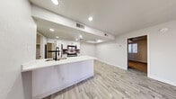 Located at 2121 W Main St in Mesa, AZ, this thoughtfully designed one-bedroom, one-bathroom unit offers a clean, modern aesthetic throughout its efficiently utilized single-floor layout. The open-concept kitchen and living area serves as the heart of the unit, featuring a crisp white peninsula with an undermount sink and matte black faucet, white shaker-style cabinetry, gray tile backsplash, and a full suite of stainless steel appliances including a refrigerator, range, and over-the-range microwave. Recessed lighting illuminates the space, which is finished with light wood-style luxury vinyl flooring that extends into the living area. The living room is bright and open, highlighted by a sliding glass door with vertical blinds that invites natural light and provides outdoor access. The generously sized primary bedroom is carpeted for comfort and includes a window with blinds, offering natural light, and direct access to the full bathroom. The bathroom features a combined tub and shower, a vanity with storage, and matching light wood-style flooring. A dedicated laundry area with washer and dryer hookups adds everyday convenience. The unit's neutral color palette and modern finishes create a clean, cohesive ambiance throughout.