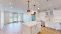 Located at 1371 Schilling Blvd W in Collierville, TN, this thoughtfully designed 2-bedroom, 2-bathroom single-story home offers a clean, modern aesthetic with high-quality finishes throughout. The open-concept kitchen and living area serves as the heart of the home, showcasing white shaker cabinetry, gleaming white quartz countertops, a central kitchen island, and stainless steel appliances including a refrigerator, range, microwave, and dishwasher. Striking gold pendant lights hang above the island, adding a warm, contemporary touch. Light hardwood flooring flows seamlessly through the main living spaces, complementing the bright, neutral color palette. The living area benefits from natural light through large glass doors that open to an outdoor view. Both bedrooms are well-proportioned, featuring ceiling fans, large windows with blinds, and hardwood flooring. The primary bedroom connects to a spacious en-suite bathroom with a dual-sink white vanity, marble-style tile flooring, a glass-enclosed shower, and a walk-in closet outfitted with multi-level wire shelving. The second bathroom features a full soaking tub and shower combo, a dual-sink vanity, and matching marble-style tile. The layout also includes a hallway and two closets, ensuring ample storage throughout.