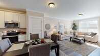 Located at 189 Paddlers Pt in Matamoras, PA, this single-floor residence offers a thoughtfully designed layout with a warm, neutral palette and hardwood-style flooring throughout. The open-concept living and dining area is anchored by crown molding, flush-mount lighting, and generous natural light streaming through window treatments. The living room accommodates comfortable seating arrangements and connects seamlessly to the dining space, which features a dark wood table and upholstered chairs. The kitchen is outfitted with crisp white cabinetry, granite countertops, and a full suite of stainless steel appliances, including a side-by-side refrigerator, range, and over-the-range microwave. A versatile flex room with a ceiling fan and ample natural light serves well as a home office or secondary dining space. The primary bedroom is generously proportioned, featuring a ceiling fan, large windows, and direct access to an en-suite bathroom with a granite vanity, white cabinetry, and a glass-enclosed tub/shower combination. A second bathroom offers a standalone walk-in shower and matching granite vanity. Throughout the residence, crown molding, consistent flooring, and a cohesive neutral tone contribute to a polished, move-in-ready atmosphere.