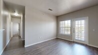 This single-floor residence in San Antonio, TX offers a practical and well-organized layout with four bedrooms, two bathrooms, a kitchen, and a living room. The living area features durable wood-look flooring, neutral-toned walls, and a textured ceiling, with large windows and a glass-panel exterior door that invite abundant natural light and outdoor views. The galley-style kitchen is equipped with warm wood cabinetry, black appliances including a range and refrigerator, light countertops, and a sink with a dishwasher — all set on easy-care hard flooring. The bedrooms offer plush carpeting and neutral walls, with windows providing natural light and exterior views; the primary bedroom includes a dedicated entry door and recessed lighting. Both bathrooms are finished with warm wood vanities, speckled countertops, single-basin sinks, large mirrors, and hard flooring. One bathroom includes a full tub-shower combination with overhead cabinetry for additional storage. Throughout the residence, clean white trim, consistent neutral tones, and practical finishes create a cohesive and move-in-ready aesthetic suited to everyday living.