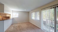 This single-floor residence offers a well-organized layout designed for comfortable everyday living. The spacious living area is finished with neutral-toned carpet and features a large sliding glass door flanked by a wide window, allowing generous natural light and views of the surrounding greenery. A secondary window further brightens the space, creating an open and airy atmosphere throughout.

The kitchen is equipped with white cabinetry, a full suite of appliances including a refrigerator, electric range, and dishwasher, complemented by a classic tile backsplash and warm hardwood flooring. A window above the sink adds additional light to the functional workspace.

The bedrooms are carpeted and finished in soft, neutral tones. One bedroom features multiple windows on adjacent walls and a walk-in closet, providing ample storage. Additional bedrooms offer individual windows with views of the exterior and are well-suited for a variety of uses.

The bathroom is cleanly finished with white tile surrounding a full tub-and-shower combination, chrome fixtures, and hardwood flooring, lending a crisp, functional aesthetic. Clean white trim and consistent neutral wall tones unify the interior throughout, creating a cohesive and move-in ready living environment.