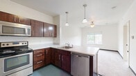 This two-story residence at 412 Welch Ave in Ames, Iowa offers a practical and well-organized layout spread across two equally sized floors. The entry level features a functional kitchen equipped with rich dark-wood cabinetry, stainless steel appliances including a refrigerator, range, microwave, and dishwasher, and durable blue-gray tile flooring that extends through the main living areas. A dedicated in-unit laundry room with a full-size washer and dryer adds everyday convenience. Three bathrooms are distributed throughout the home, each finished with dark-wood vanities, white countertops, and tile flooring; one features a full tub-shower combination. The upper floor hosts two carpeted bedrooms, each fitted with ceiling fans and windows that invite natural light and neighborhood views. The spacious primary bedroom offers a notably generous footprint. A hallway, staircase, and two closets round out the floor plan, providing ample storage and circulation space. The overall aesthetic is clean and modern, with white walls, dark baseboards, and consistent finishes throughout, creating a cohesive and move-in-ready living environment.