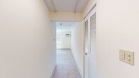 This studio unit in Seabrook, New Hampshire offers a practical and efficiently laid-out single-floor living space. The generously sized main living area features soft carpeted flooring, neutral cream-toned walls, and a textured ceiling, creating a clean and understated ambiance. A large sliding window allows natural light to fill the room while offering views of the surrounding residential community, and a wall-mounted air conditioning unit alongside baseboard heating ensures year-round comfort. The kitchen is outfitted with warm-toned wood cabinetry, granite-style countertops, and wood-look vinyl flooring, giving it a functional yet appealing character. A full-size refrigerator and ample counter space make it well-suited for everyday use. The bathroom features a tiled tub-shower combination with classic white tilework, wood-look flooring, and clean, simple fixtures that provide a practical and tidy space. The bedroom is notably spacious for a studio-style unit, offering room for a full bedroom setup with its plush carpeting and baseboard heating. The overall layout transitions smoothly between areas, making efficient use of every square foot throughout this straightforward and move-in ready unit.