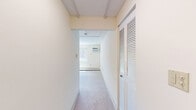 This studio unit in Seabrook, New Hampshire offers a practical and efficiently laid-out single-floor living space. The generously sized main living area features soft carpeted flooring, neutral cream-toned walls, and a textured ceiling, creating a clean and understated ambiance. A large sliding window allows natural light to fill the room while offering views of the surrounding residential community, and a wall-mounted air conditioning unit alongside baseboard heating ensures year-round comfort. The kitchen is outfitted with warm-toned wood cabinetry, granite-style countertops, and wood-look vinyl flooring, giving it a functional yet appealing character. A full-size refrigerator and ample counter space make it well-suited for everyday use. The bathroom features a tiled tub-shower combination with classic white tilework, wood-look flooring, and clean, simple fixtures that provide a practical and tidy space. The bedroom is notably spacious for a studio-style unit, offering room for a full bedroom setup with its plush carpeting and baseboard heating. The overall layout transitions smoothly between areas, making efficient use of every square foot throughout this straightforward and move-in ready unit.
