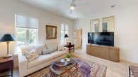 Located at 2613 Montgomery St in Savannah, Georgia, this single-floor, 2-bedroom, 2-bathroom residence offers a thoughtfully designed layout with modern finishes throughout. The bright living room features light hardwood flooring, large windows that invite natural light, and a ceiling fan, creating an airy and welcoming atmosphere. The open kitchen is outfitted with stainless steel appliances including a full-size refrigerator, range, and built-in microwave, complemented by sleek sage-grey cabinetry, white quartz countertops, a peninsula with seating, and pendant lighting. The primary bedroom offers generous proportions, access to a private balcony via French doors, and a dedicated en-suite bathroom featuring a double vanity with sage-grey cabinetry, black hardware accents, and a glass-enclosed shower. The second bathroom is equally refined, with a floating white vanity, large-format light tile flooring, and a tiled walk-in shower. Both bedrooms are served by well-organized closets, including a spacious walk-in closet with wire shelving. Clean white walls, light wood floors, and black hardware details create a cohesive, contemporary aesthetic throughout the entire residence.