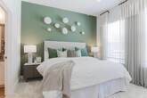 Located at 2–14 S Clayton St in Lawrenceville, GA, this single-story residence offers a well-appointed interior defined by contemporary finishes and a cohesive neutral color palette throughout. The living room serves as a welcoming centerpiece, featuring large windows dressed with sheer curtains and blinds that invite generous natural light. A fireplace anchors one wall, complementing the open, comfortable layout.

The kitchen is thoughtfully designed with white shaker cabinetry extending to the ceiling, granite countertops, and stainless steel appliances including a range, microwave, refrigerator, and dishwasher. A peninsula with an undermount sink and pendant lighting above adds both function and style, while wood-look flooring ties the space together seamlessly.

The bedrooms are carpeted for comfort and feature large windows with layered window treatments. One bedroom showcases a bold deep-green accent wall, while another offers a more neutral aesthetic, both providing a restful atmosphere. The bathroom includes a glass-enclosed walk-in shower with large-format tile, a granite-topped vanity, wood-look flooring, and direct access to a spacious walk-in closet with multi-tiered shelving. Overall, the residence presents a polished, modern living environment.