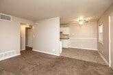 This single-floor residential unit offers a practical and well-organized layout designed for comfortable everyday living. The open living area is finished with warm wall-to-wall carpeting and a textured ceiling, with a ceiling fan providing efficient air circulation. A partial dividing wall separates the living space from the adjacent dining and kitchen area, creating a sense of definition while maintaining an open feel. The galley-style kitchen is efficiently arranged with white cabinetry lining both sides, providing ample upper and lower storage. Laminate countertops offer generous workspace, and the kitchen is equipped with a white electric range and refrigerator, complemented by tile-style flooring for easy maintenance. The bedrooms are carpeted and feature ceiling fans, with windows that allow natural light to brighten each room. One bedroom includes a closet and an adjoining door that connects conveniently to additional spaces. The bathroom is clean and straightforward, featuring a full tub and shower combination with white surround panels, a toilet, and tile flooring. Throughout the unit, neutral gray walls and white trim create a cohesive, move-in-ready aesthetic. Ceiling vents indicate a central HVAC system, and a wall-mounted air conditioning unit is also present in one room, offering additional climate control flexibility.