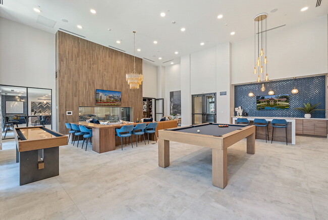 Clubhouse with plush seating, large fireplace and pool table with floor to ceiling windows. - LIVIA at Scripps Ranch