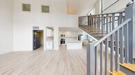 Located at 1000 Washington Ave in downtown St. Louis, this two-story residence offers a thoughtfully designed layout spread across two floors. The main level makes an immediate impression with its soaring double-height ceilings and an open-concept living and dining area bathed in natural light. Light-toned luxury vinyl plank flooring flows seamlessly throughout, complementing the bright, neutral palette of the space.

The kitchen is a standout feature, showcasing crisp white shaker cabinetry extending to the ceiling, generous counter space with clean white quartz surfaces, and stainless steel appliances including a range, built-in microwave, dishwasher, and refrigerator. A central island provides additional prep and seating space. A stylish staircase with gray railings and warm wood accents connects the two floors, adding architectural interest to the open main level.

The upper floor houses the spacious primary bedroom alongside a dedicated laundry room with full-size washer and dryer. Two well-sized closets offer ample storage, including a generous walk-in. Both bathrooms are finished with modern floating vanities, dark hardware accents, and contemporary lighting. The space also includes a utility room, adding further functionality to this well-equipped St. Louis residence.