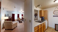 Located at 3475 American Dr in Colorado Springs, CO, this one-bedroom, one-bathroom residence offers a thoughtfully designed single-level layout. The open-concept living and dining area is bright and inviting, featuring plush carpeting, a ceiling fan, and large windows dressed with bold red curtains that allow ample natural light. The space flows seamlessly into the galley-style kitchen, which is outfitted with warm oak cabinetry, light countertops, a double-basin sink, a full-size refrigerator, an electric range, a dishwasher, and a microwave — providing generous storage and functionality. A pass-through counter connects the kitchen to the dining and living areas, enhancing the open feel. The bedroom is a comfortable retreat highlighted by a warm terracotta accent wall, plush carpet, and a ceiling fan. It offers room for a full furniture suite and connects to the hallway with a solid wood door. The full bathroom features a single-sink oak vanity with a large mirror, a tub/shower combination, tile flooring, and the added convenience of a stacked in-unit washer and dryer. Throughout the residence, neutral tones and consistent finishes create a cohesive and welcoming ambiance.