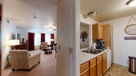 Located at 3475 American Dr in Colorado Springs, CO, this one-bedroom, one-bathroom residence offers a thoughtfully designed single-level layout. The open-concept living and dining area is bright and inviting, featuring plush carpeting, a ceiling fan, and large windows dressed with bold red curtains that allow ample natural light. The space flows seamlessly into the galley-style kitchen, which is outfitted with warm oak cabinetry, light countertops, a double-basin sink, a full-size refrigerator, an electric range, a dishwasher, and a microwave — providing generous storage and functionality. A pass-through counter connects the kitchen to the dining and living areas, enhancing the open feel. The bedroom is a comfortable retreat highlighted by a warm terracotta accent wall, plush carpet, and a ceiling fan. It offers room for a full furniture suite and connects to the hallway with a solid wood door. The full bathroom features a single-sink oak vanity with a large mirror, a tub/shower combination, tile flooring, and the added convenience of a stacked in-unit washer and dryer. Throughout the residence, neutral tones and consistent finishes create a cohesive and welcoming ambiance.