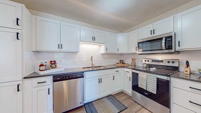Kitchen with white cabinets and stainless steel appliances - Creekside Apartments