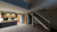 Located at 4880 Willow Glen Dr in Beech Grove, Indiana, this two-story residence offers a practical and functional layout divided evenly between its two floors. The main level houses the kitchen and living areas, while a striking open staircase with black metal balusters and a white handrail connects the floors, adding a visual focal point to the interior.

The kitchen is well-equipped with warm-toned wood cabinetry offering ample storage, light laminate countertops, and black appliances including a refrigerator, electric range, over-the-range microwave, and dishwasher. A skylight overhead brightens the space with natural light, and light-toned vinyl plank flooring ties the area together.

The living room features neutral gray walls, plush carpeting, and a textured ceiling, creating a comfortable, understated atmosphere. Closet doors are visible along the main floor wall, providing convenient storage solutions.

The upper level opens to a loft-style space with sloped ceilings that follow the roofline, carpeted flooring, and an open railing overlooking the stairwell. Windows allow natural light to filter in, enhancing the airy feel of the upper floor.

The bathroom includes a full tub-shower combination with clean white surround, a toilet, and light tile-style flooring, offering a simple and functional design throughout.