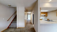 Located at 209 N Kendall Ave in Kalamazoo, Michigan, this two-story home offers four bedrooms and two full bathrooms across two well-proportioned floors of living space. The main floor features a kitchen equipped with warm wood cabinetry, white appliances including a range and dishwasher, a skylight panel ceiling, and an extended breakfast bar that opens to the adjacent living area. The living room is a comfortable retreat highlighted by a freestanding electric fireplace with a wood mantle and large sliding glass doors that invite natural light and provide views of the surrounding greenery. Hardwood flooring anchors the main living areas, while plush carpeting carries throughout the upper level. Both bathrooms are finished with tile flooring and warm wood vanities; one features a tub-shower combo with full tile surround, while the other offers a jetted soaking tub. The four bedrooms are carpeted and each includes a built-in sliding-door closet, with warm wood trim framing the doorways throughout. A staircase connects the two floors, with hallways on each level providing efficient circulation. The home's layout is practical and functional, offering comfortable everyday living in a quiet Kalamazoo neighborhood.