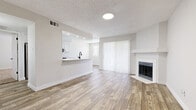 This single-floor residence offers a thoughtfully designed layout with a bright, open-concept living and dining area at its heart. Wood-look flooring flows throughout the main living spaces, complementing the neutral, light-toned walls and textured ceilings. A white-mantled fireplace anchors one end of the living room, while a pass-through breakfast bar connects seamlessly to the kitchen. Sliding glass doors dressed in vertical blinds invite natural light and provide easy access to the outdoors.

The kitchen is well-equipped with crisp white shaker cabinetry, matte black hardware, light quartz countertops, and a full suite of stainless steel appliances including a refrigerator, range, microwave, and dishwasher. Wood-look flooring continues through this space, reinforcing the cohesive aesthetic.

The bedrooms offer comfortable, carpeted retreats, each fitted with ceiling fans and natural light from windows with blinds. The primary bedroom includes a walk-in closet and an en-suite bathroom, while additional bedrooms provide built-in closet storage. Bathrooms feature white vanity cabinetry with matte black hardware, quartz countertops, and warm-toned wood-look flooring, creating a clean, modern feel throughout.
