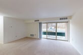 Located at 13202 Twinbrook Pkwy in Rockville, MD, this single-floor, one-bedroom, one-bathroom residence offers a thoughtfully arranged layout with comfortable living spaces throughout. The open-plan living and dining area is carpeted and bathed in natural light, anchored by a large sliding glass door that opens to a balcony overlooking a wooded outdoor setting — an inviting feature that brings nature into everyday living. A pendant light fixture marks the dining zone, adding a subtle design touch to the combined space. The kitchen features warm hardwood-style flooring, white shaker cabinetry, granite-look countertops, a gas range, and a full-size refrigerator, offering a clean and functional cooking environment. The generously sized bedroom is carpeted and bright, with a window framing peaceful outdoor views, and provides access to two closets for ample storage. A hallway connects the main living areas to the full bathroom, which is finished with classic white tile and a bold black-and-white checkered accent border above the bathtub/shower combination. The unit's neutral color palette and consistent finishes create a clean, move-in ready ambiance throughout.