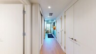 Located at 3401 S La Cienega Blvd in Los Angeles, this thoughtfully designed one-bedroom, one-bathroom unit offers a smart and efficient use of space across a single floor. The open-plan living and kitchen area serves as the heart of the home, featuring light hardwood flooring, a sleek kitchen with soft gray cabinetry, stainless steel appliances including a full-size refrigerator and range, and under-cabinet lighting that adds warmth to the space. A compact dining area and a cozy living zone with a curved sofa complete the communal space, accented by a decorative slatted wood wall panel that adds texture and visual interest. The spacious primary bedroom is bathed in soft, neutral tones with clean white walls, warm carpeting, and curated artwork, creating a calm and restful atmosphere. The bathroom is a design highlight, featuring a striking checkerboard tile floor, floor-to-ceiling mosaic tile in the walk-in glass-enclosed shower, a floating wood vanity, and a backlit mirror. A standout feature of this unit is the private balcony, which offers stunning elevated views of a resort-style pool deck below and the rolling Los Angeles hills beyond, under wide open skies.
