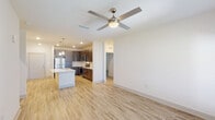 This single-story, three-bedroom, two-bathroom unit in Gulf Breeze, Florida offers a well-designed open-concept floor plan that maximizes functionality and flow. Light wood-look flooring runs throughout the main living areas, complementing the bright, neutral color palette that defines the interior aesthetic.

The kitchen serves as the focal point of the main living area, featuring dark espresso-toned cabinetry extending to the ceiling for ample storage, stainless steel appliances including a refrigerator, electric range, and built-in microwave, and a white quartz-topped island with an integrated sink and pendant lighting overhead. The kitchen opens directly into the living area, which is fitted with a ceiling fan and a window offering natural light.

Both bathrooms maintain the clean, modern aesthetic of the unit. The primary bathroom includes a glass-enclosed walk-in shower and light wood-look flooring, while the secondary bathroom features a white quartz vanity countertop with dark cabinetry below.

Each of the three bedrooms is carpeted and equipped with a ceiling fan and window with blinds, providing a comfortable, quiet retreat. The overall design emphasizes a clean, contemporary style throughout.