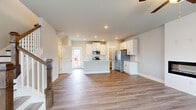 This two-story home in Opelika, Alabama is thoughtfully designed across two floors, offering a practical and modern layout suited for comfortable everyday living. The main floor hosts the open-concept living and kitchen area, where light-toned hardwood-style flooring flows throughout. The living room features a sleek, built-in linear fireplace set into a clean white surround, complemented by a ceiling fan and a window that brings in natural light. The kitchen is a standout space, showcasing white shaker-style cabinetry, a granite-topped island with an integrated sink, subway tile backsplash, stainless steel appliances, and recessed lighting. A door from the kitchen provides direct exterior access. The main floor also includes hallways, a bathroom, and a dedicated laundry room equipped with a full-size washer and dryer. Upstairs, two bedrooms are finished with plush carpet and multiple windows offering outdoor views. The primary bedroom includes a closet and access to a private bathroom featuring a glass-enclosed shower and granite vanity. An additional full bathroom with a soaking tub and shower serves the upper level. Three bathrooms in total ensure convenience throughout the home.