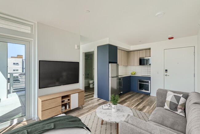 Experience the open and inviting living space at Anker Ballard, featuring modern furniture, a spacious layout, and a seamless transition between the living room and kitchen. - Anker Ballard